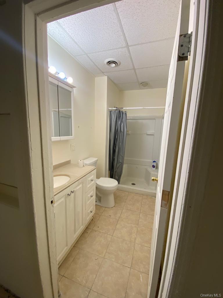 Bathroom featuring a paneled ceiling, a stall shower, vanity, and light tile patterned flooring