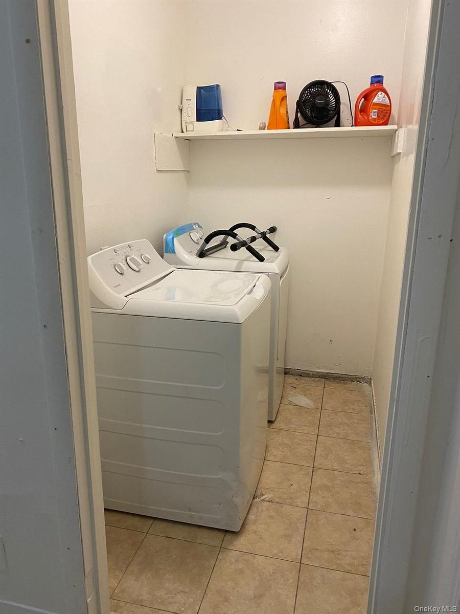 Laundry area with light tile patterned floors and independent washer and dryer