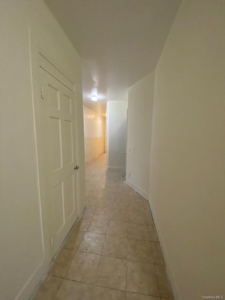 Corridor featuring light tile patterned flooring and baseboards