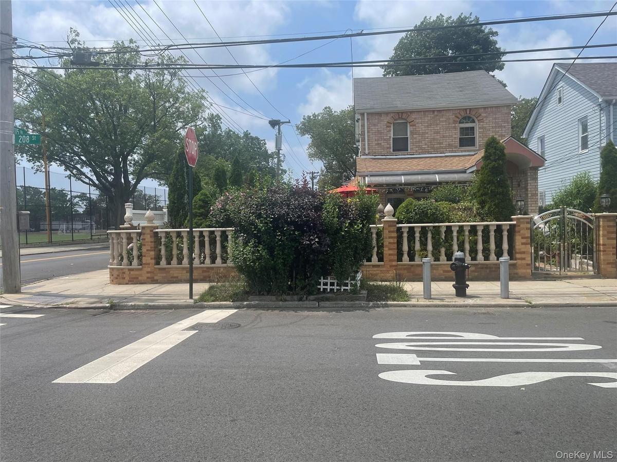 View of asphalt road with sidewalks, curbs, a gate, and traffic signs
