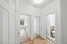 Corridor featuring light wood-style floors, ornamental molding, and tile walls
