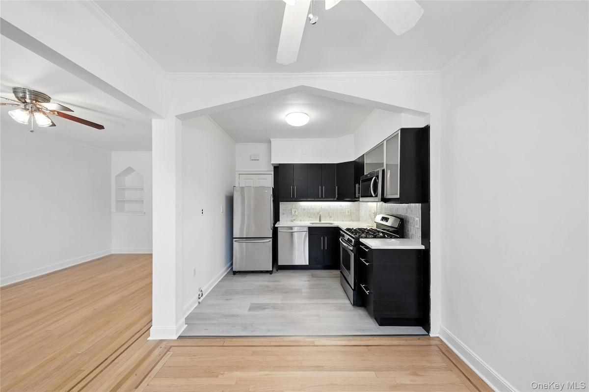 Kitchen featuring dark cabinets, ceiling fan, appliances with stainless steel finishes, tasteful backsplash, and crown molding