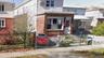 View of front of property with brick siding, a fenced front yard, and a gate