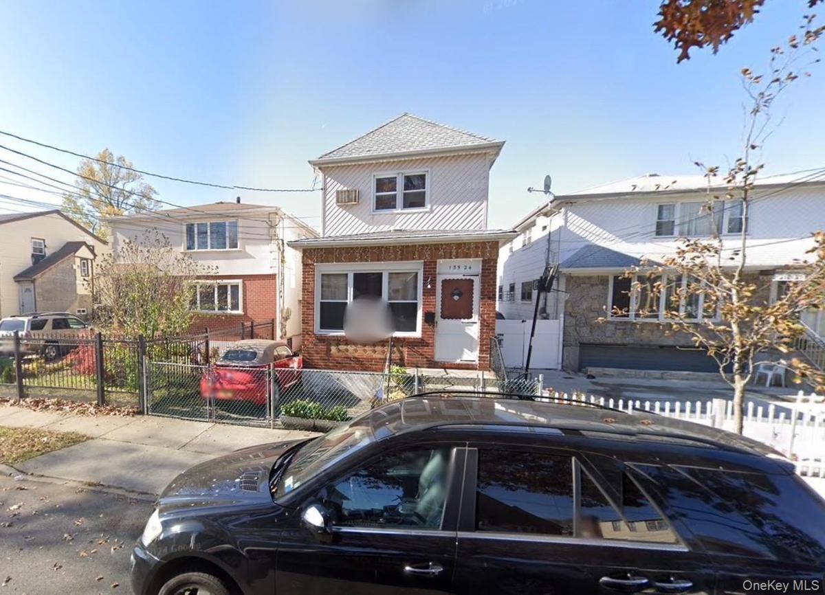 View of front of home with a fenced front yard, brick siding, and a gate