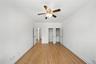 Unfurnished bedroom with light wood-style floors, ceiling fan, crown molding, and two closets