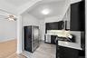 Kitchen featuring dark cabinets, stainless steel appliances, light wood finished floors, crown molding, and light stone counters