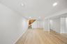 Finished basement featuring light wood-style flooring, stairway, and recessed lighting