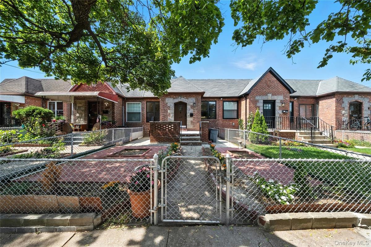 View of front of home featuring a gate, a fenced front yard, brick siding, and roof with shingles