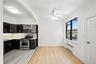 Kitchen with dark cabinetry, light wood finished floors, appliances with stainless steel finishes, glass insert cabinets, and backsplash