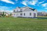Rear view of property with board and batten siding, covered porch, a shingled roof, driveway, and an attached garage. For Marketing Purposes!