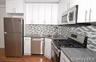 Kitchen with appliances with stainless steel finishes, white cabinetry, decorative backsplash, and dark wood-type flooring