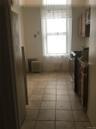 Kitchen featuring radiator, light tile patterned flooring, brown cabinets, and gas range