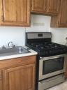 Kitchen with stainless steel gas stove, brown cabinets, and light countertops