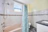 Full bath with shower / bath combo, vanity, tile walls, and marble look tile flooring