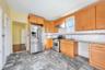 Kitchen with stainless steel appliances, light stone countertops, under cabinet range hood, decorative backsplash, and a heating unit