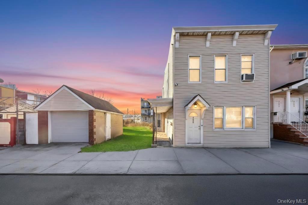 View of front of property with an outdoor structure, a detached garage, concrete driveway, and a front yard