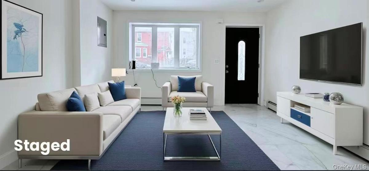 Living area with marble look tiles, a baseboard radiator, baseboard heating, and electric panel
