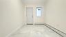 Empty room featuring a baseboard heating unit, light marble finish floors, and lofted ceiling