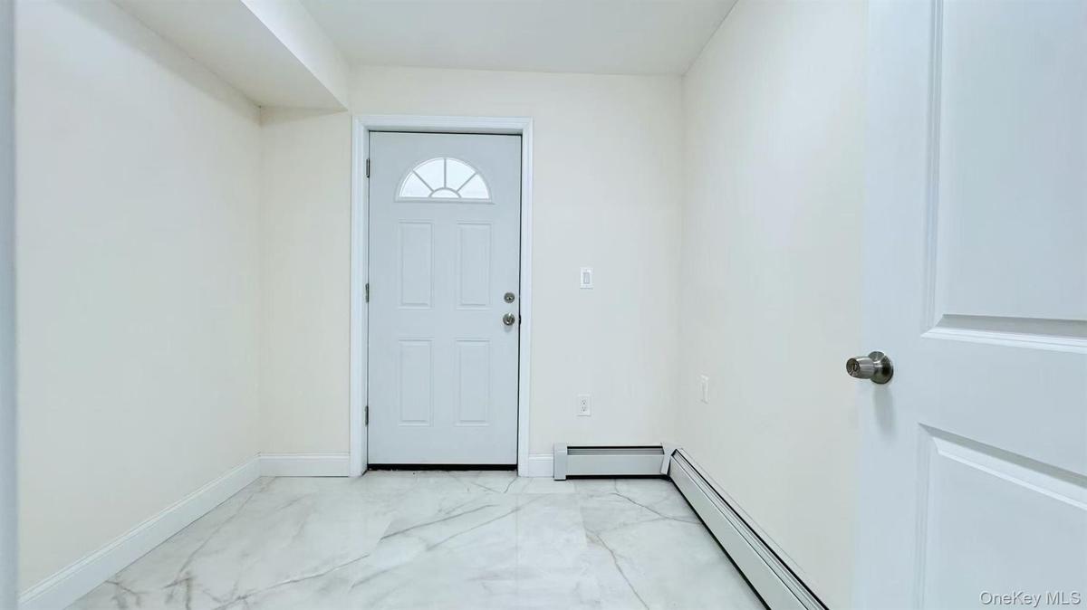 Foyer featuring light marble finish floors and baseboard heating
