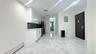 Kitchen with white cabinets, a baseboard heating unit, light marble finish flooring, electric panel, and tasteful backsplash