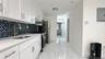 Kitchen featuring white cabinetry, light stone countertops, stainless steel gas range, electric panel, and light marble finish floors