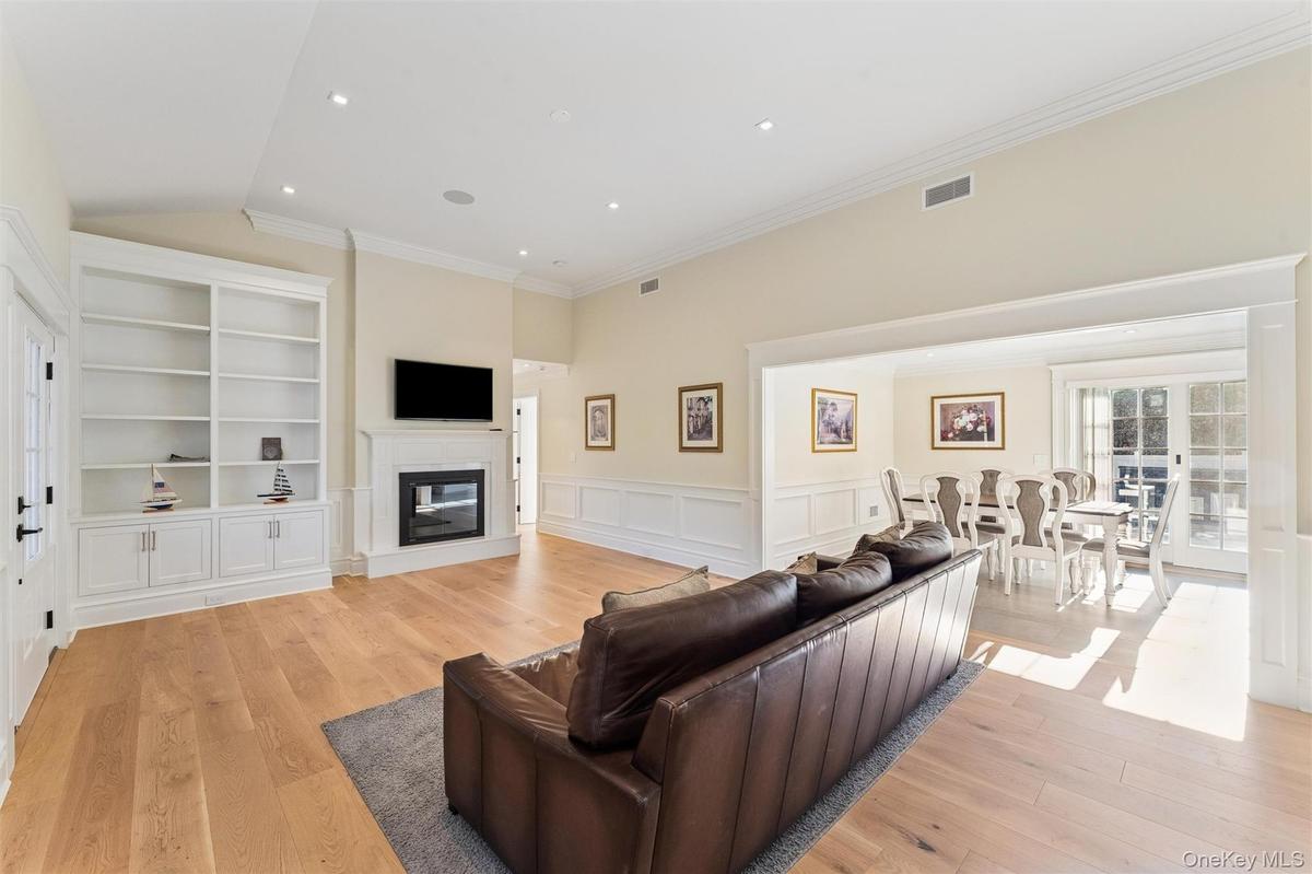 Living room with a wainscoted walls, light wood flooring, and a glass covered fireplace.