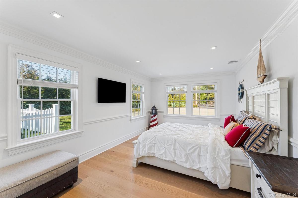 Bedroom with light wood floors and wainscoted walls.