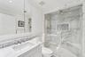 Bathroom inside primary bedroom with crown molding, custom vanity, marble finish shower, tile walls, and a stunning backsplash.
