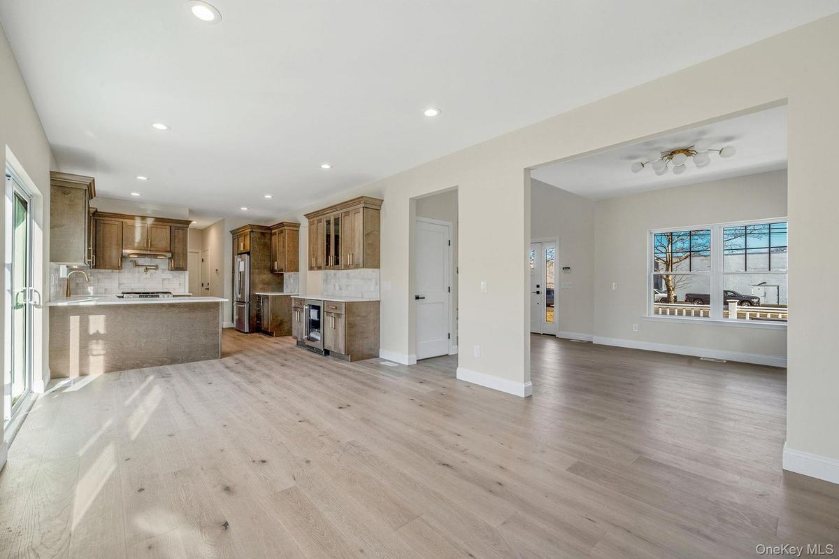 Unfurnished living room with light wood-type flooring, wine cooler, and recessed lighting. For Marketing Purposes!