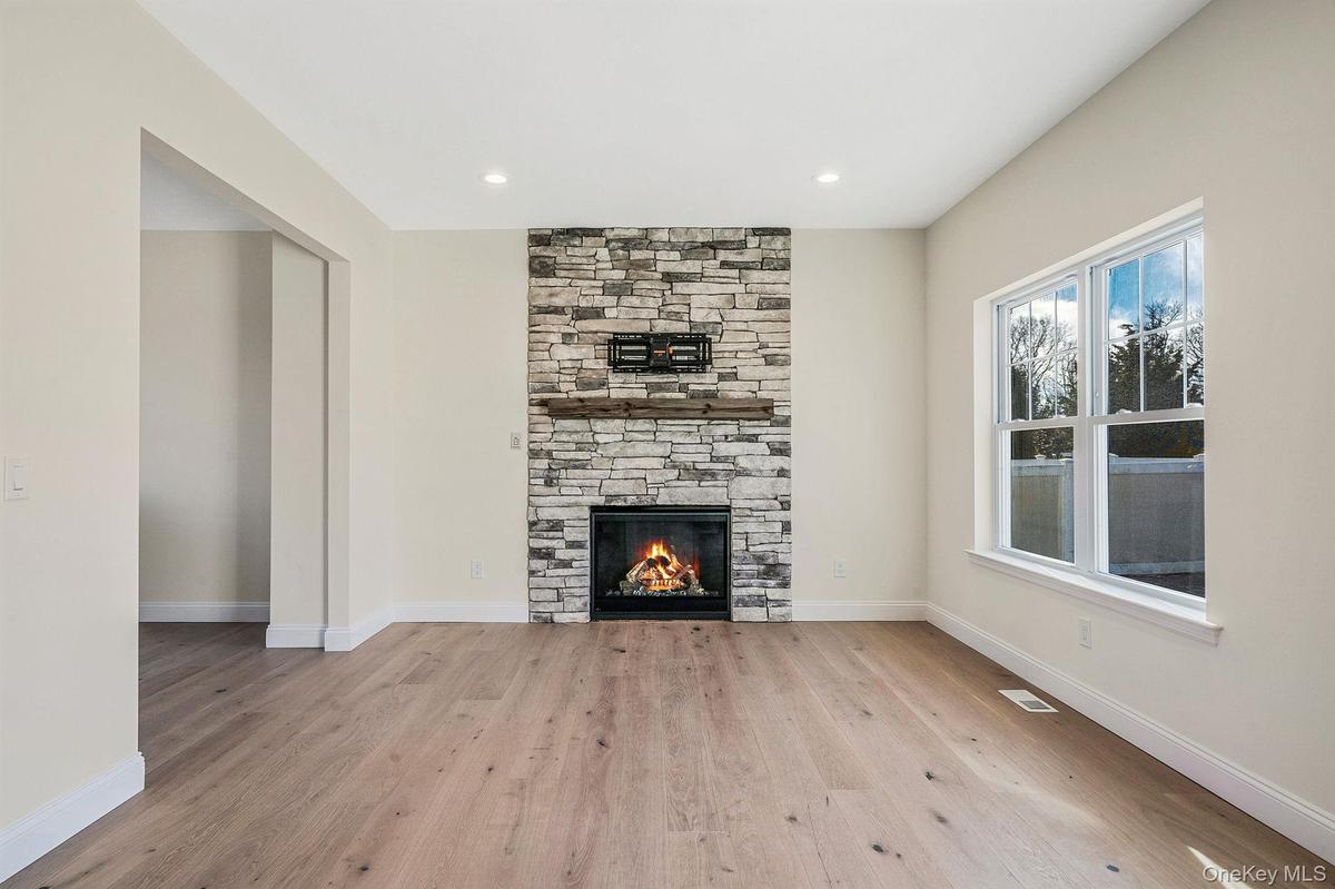Unfurnished living room featuring a stone fireplace, light wood-type flooring, and recessed lighting. For Marketing Purposes!