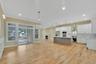 Kitchen featuring open floor plan, white cabinetry, hanging light fixtures, wall chimney range hood, and a center island. For Marketing Purposes!