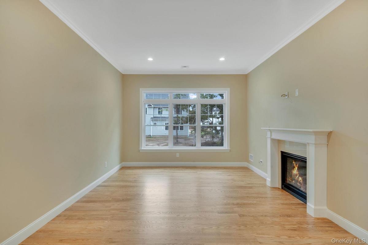 Unfurnished living room with a glass covered fireplace, light wood-type . For Marketing Purposes!flooring, ornamental molding, and recessed lighting