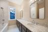 Bathroom featuring double vanity, light marble finish floors, and a combined bath / shower with marble appearance. For Marketing Purposes!