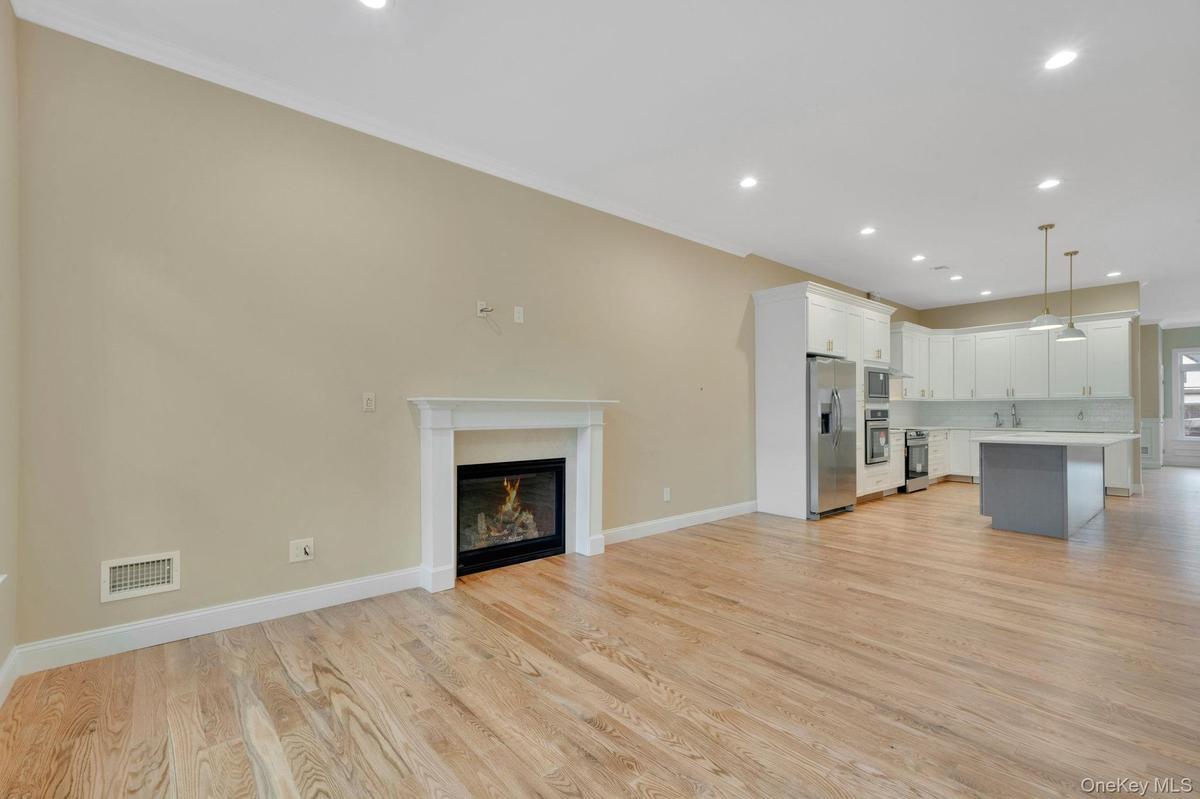 Unfurnished living room featuring recessed lighting, light wood-type flooring, a glass covered fireplace, and ornamental molding. For Marketing Purpos
