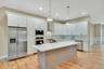 Kitchen featuring appliances with stainless steel finishes, crown molding, white cabinetry, pendant lighting, and a center island. For Marketing Purpo