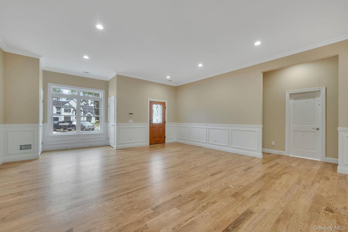 Unfurnished living room featuring wainscoting, recessed lighting, light wood-style floors, ornamental molding, and a decorative wall. For Marketing Pu