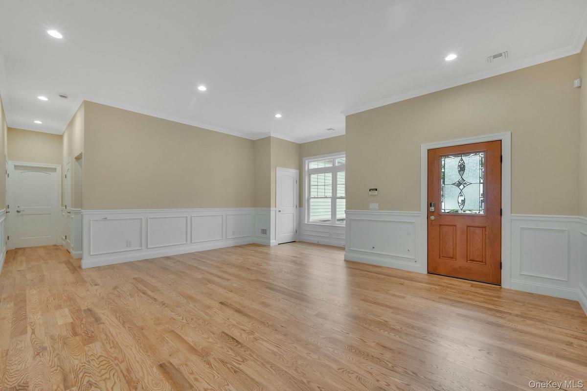 Foyer entrance with wainscoting, light wood-style flooring, a decorative wall, and crown molding. For Marketing Purposes!