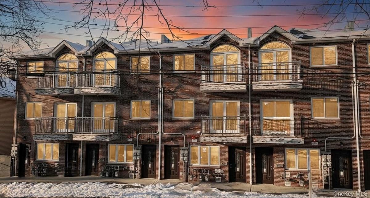 View of front facade featuring a balcony and brick siding