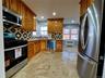 Kitchen featuring appliances with stainless steel finishes, brown cabinets, tasteful backsplash, recessed lighting, and stone tile floors