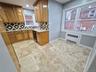 Kitchen featuring brown cabinets, decorative backsplash, light stone counters, radiator, and recessed lighting