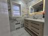 Bathroom with vanity, radiator heating unit, crown molding, and light marble finish flooring