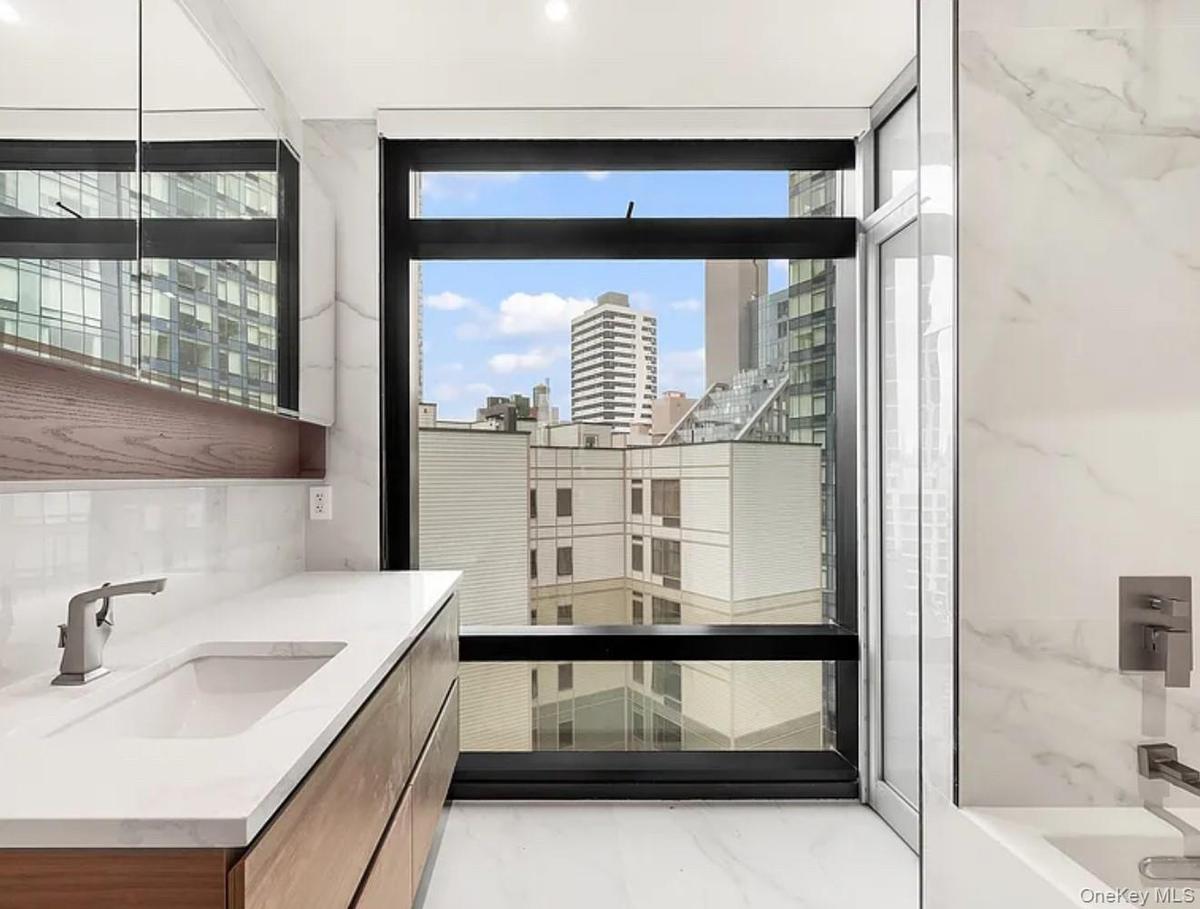 Bathroom with a view of city, vanity, light marble finish floors, walk in shower, and a bathtub