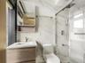 Bathroom featuring a marble finish shower, tile walls, and vanity