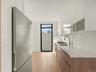 Kitchen featuring modern cabinets, stainless steel appliances, light stone counters, and light wood-style floors
