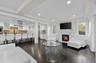 Living room with dark wood-style floors, a glass covered fireplace, recessed lighting, and crown molding