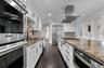 Kitchen featuring stainless steel appliances, crown molding, dark stone counters, range hood, and white cabinetry