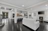 Living area with a glass covered fireplace, recessed lighting, dark wood-style floors, crown molding, and stairway