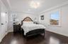 Bedroom featuring crown molding, dark wood-style floors, a chandelier, a raised ceiling, and recessed lighting