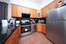 Kitchen featuring appliances with stainless steel finishes, dark aggregate flooring, extractor fan, glass insert cabinets, and brown cabinets