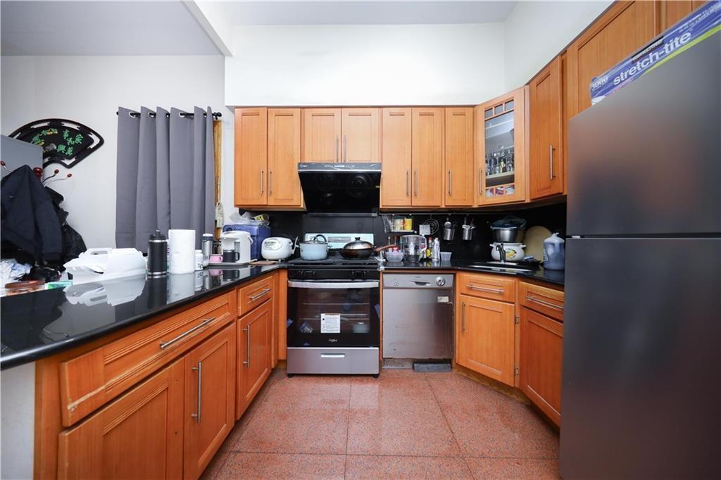 Kitchen with stainless steel appliances, dark countertops, glass insert cabinets, and brown cabinets